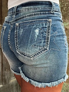 Detail of blue denim shorts showing white star embroidery and distressed frayed hem