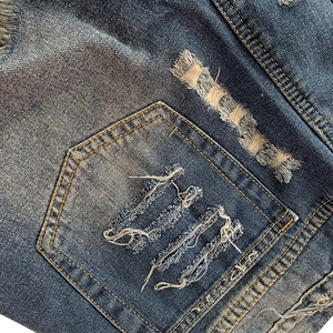 Détail de la poche arrière en denim vieilli avec délavage vintage et coutures dorées