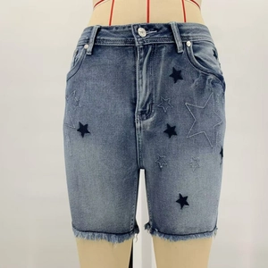 Detail of embroidered star patterns and frayed raw hem on blue denim shorts