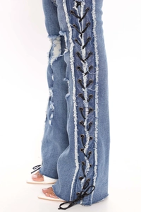 Close-up of women's blue distressed jeans with side metal eyelet lace-up details