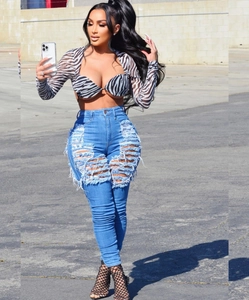 Détail de jean skinny taille haute avec déchirures prononcées et haut court à motif zébré