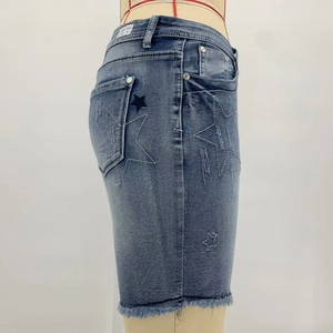 Detailed close-up of embroidered stars and frayed hem on stretchy denim shorts