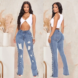 Detail of high waisted flared denim jeans with lace-up eyelets and ripped knee design