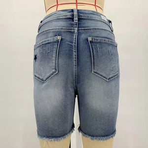 Detail of light blue denim shorts featuring star embroidery and raw fringe hems