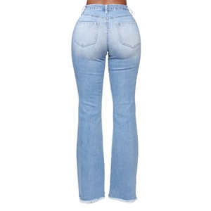 Detail of light blue flared jeans showing back pockets and raw hem edges on a model