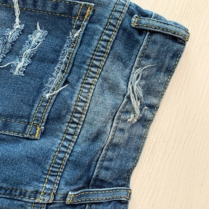 Gros plan d'un short en jean bleu délavé avec coutures orange et poches effilochées
