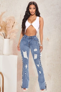 Detail of high-waisted blue slim-fit jeans featuring lace-up eyelets and ripped denim texture