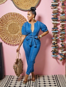 Détail d'une combinaison en jean bleu avec décolleté en V profond et ceinture nouée