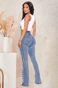Detail of high waist flared jeans with black lace-up side design and frayed edges
