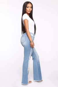 Detail of light blue flared jeans featuring unique side fringe and distressed ripped design