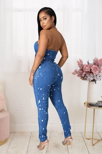 Detail view of the strapless slim denim jumpsuit with white ink splatter and back zipper