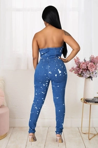 Detail view of denim strapless jumpsuit with artistic white paint splatters and back zipper