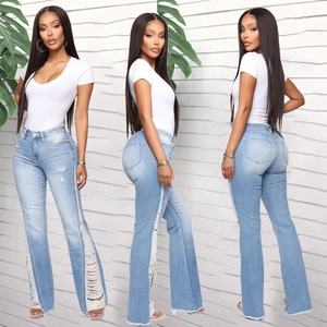 Detailed view of light blue flared jeans with ripped side cutouts and distressed fringe
