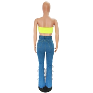 Detail of high waisted flared denim jeans featuring unique white feather fringe hem design