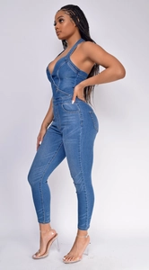 Detail view of denim halter neck jumpsuit featuring a deep V-neck and slim fit wash