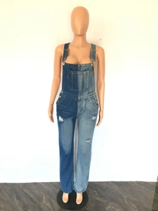 Detail of color-block denim overalls featuring distressed ripped holes and metallic buckles