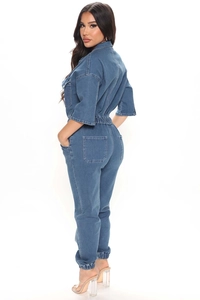 Detail of medium blue denim jumpsuit featuring utilitarian pockets and elastic waist design
