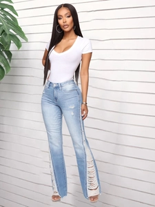 Detail view of light blue distressed flare jeans with stylish ripped holes and raw hems