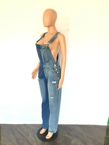 Detail of denim overalls featuring asymmetric color blocking and distressed whiskers