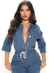 Detail of blue denim jumpsuit showing metal buttons, chest pockets and white drawstring waist