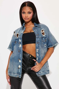 Détail de la veste en jean usée avec des trous effilochés et une texture denim vintage
