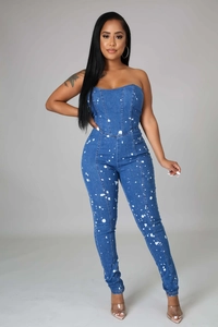 Detail view of slim-fit denim jumpsuit featuring strapless bodice and white paint splatter