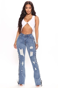 Detail of blue distressed jeans with lace-up eyelet side seams and ripped knee accents