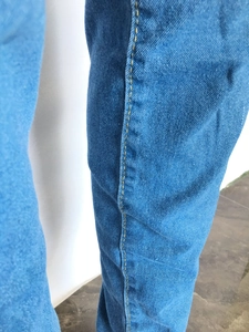 Détail du tissu denim bleu clair avec coutures jaunes contrastées sur le jean