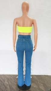 Detail view of high waist blue denim jeans with white feather trim on flare hem
