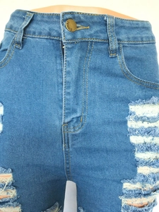 Détail du short en jean bleu à taille haute avec déchirures et bouton en métal doré