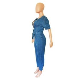 Détail d'une combinaison en jean bleu foncé avec fermeture éclair en métal et ceinture nouée