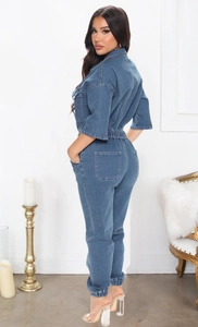 Detail view showing back pockets and elastic waist of the blue denim jumpsuit on a model