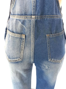Detail of slim-fit denim overalls showing asymmetrical wash design and dual back pockets