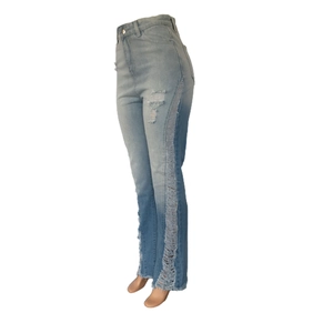 Detail showing side distressed ripped holes and fringe hem on light blue denim jeans