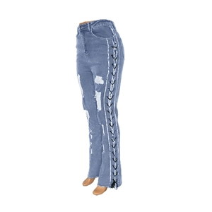 Detail of high waist skinny jeans with side lace-up eyelets and ripped denim finish