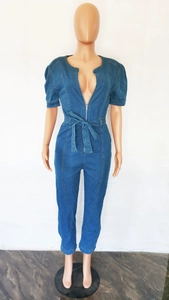 Détail d'une combinaison en jean bleu foncé avec col en V, fermeture éclair et ceinture