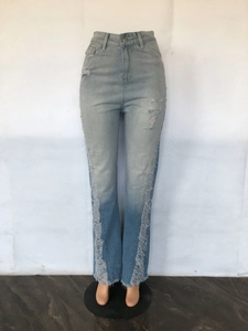 Macro detail of ripped denim fabric with distressed holes and fringe hem on light blue jeans