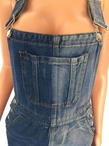Detail of denim overalls with color-block design and adjustable metal strap buckles