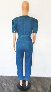 Détail des manches bouffantes courtes avec boutons en métal sur un combishort en denim