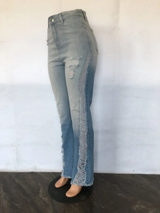 Detail of ripped distressing and frayed raw hem on light blue flared denim jeans