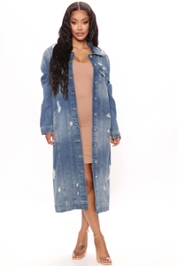 Detail shot of mid-blue distressed denim trench coat with ripped holes and button closure