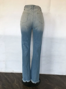Detail view of light blue washed denim jeans with back pockets and frayed raw hem edges
