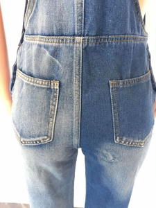 Detail view of denim overalls showing back pockets and contrasting yellow stitching detail