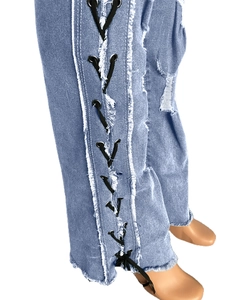 Detail view of light blue denim jeans featuring black lace-up side design and frayed edges