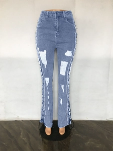 Detail of light blue ripped jeans featuring metal eyelet side lace-up and frayed hem