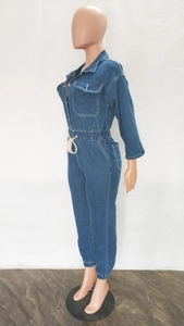 Side view of dark blue denim jumpsuit featuring elastic waist and cream drawstrings