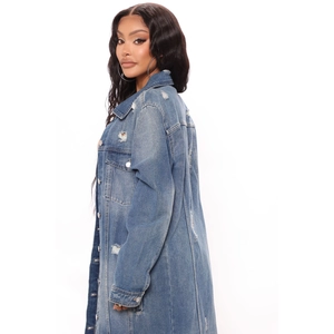 Detail of distressed medium blue denim coat with ripped holes and washed texture