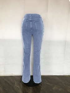 Detail of light blue washed denim pants featuring side fringe and distressed raw hems