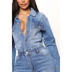 Detailed close-up of light blue wash denim jumpsuit with button front and elastic waist