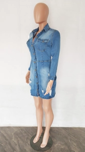 Détail d'une robe en jean moulante avec boutons métalliques et ourlet effiloché usé